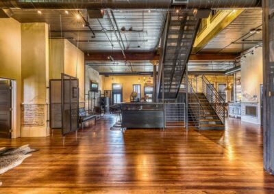 A large open space with wooden floors, a metal staircase, and exposed beams, reflecting a blend of industrial and rustic design.