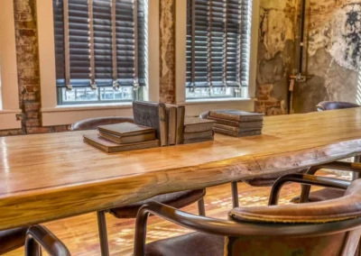 A large wooden table surrounded by chairs, with vintage books placed at the center, evoking a scholarly atmosphere.