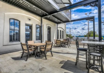 A modern patio with tables and chairs under a pergola, offering a space for relaxation with a view of the surroundings.