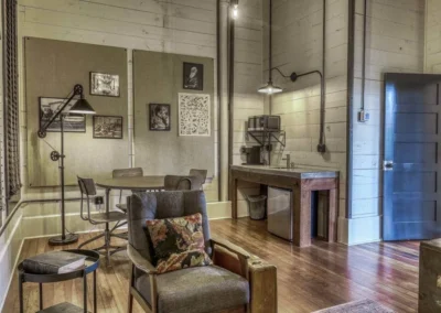 A small study space with vintage furnishings, including a desk, chair, and industrial-style lighting.