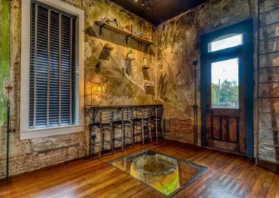 A cozy seating area with a bar counter, stools, and a historical well under glass flooring, accentuating the building's rich past.