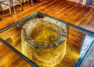 A view of an old well encased in glass flooring, showcasing the historical charm of the building.