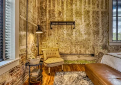 A cozy reading nook with a tufted chair, side table, and exposed brick walls, exuding vintage charm.