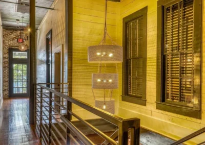 A rustic hallway with pendant lights and large windows, featuring wooden floors and industrial-style decor.